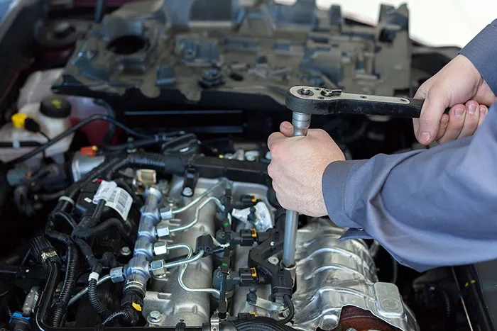 Mechanic repairing car engine with wrench