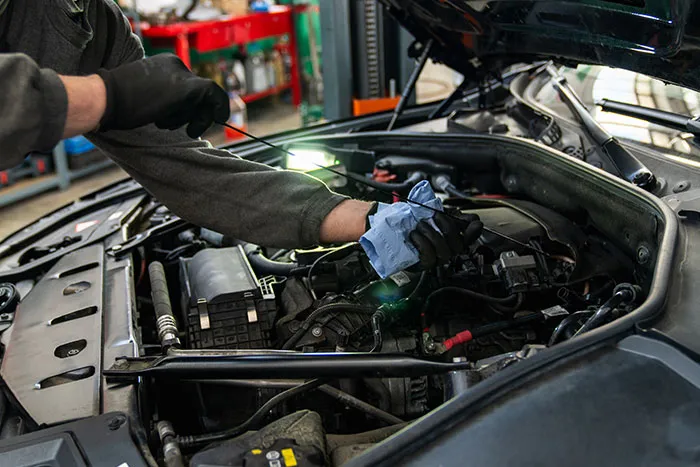 Mechanic inspecting car engine with light