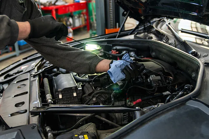 Mechanic checking car engine oil level with dipstick.