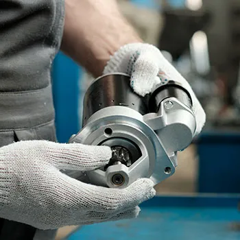 Technician inspecting automotive engine starter motor